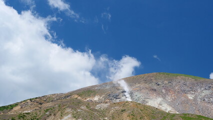 Fototapeta na wymiar 噴煙をあげる火山。日本の山。