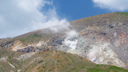 噴煙をあげる火山。日本の山。