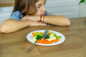 Obraz na płótnie Canvas The child eats vegetables on a chair. Selective focus.