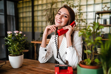Girl holding a telephone red receiver of an old landline phone