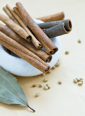 Cinnamon sticks, star anise, bay leaf and coriander seeds in a small mortar.