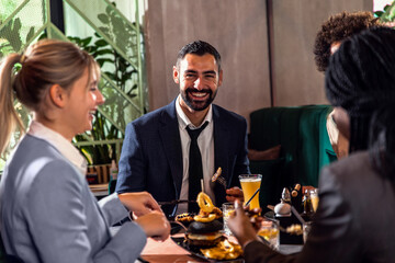 Portrait of young business man in restaurant whit his colleagues.