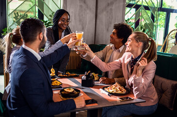 Group of businesspeople in a restaurant toasting at business lunch.