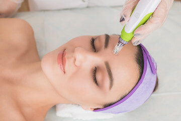 Fractional mesotherapy.A young beautiful woman in the cosmetologist’s office receives fractional...