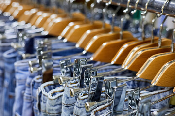 Various blue Jeans on a hanging rack in the clothes store. Close-up, selective focus