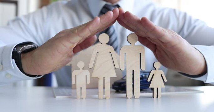 Insurance agent guards figures of family with hands closeup