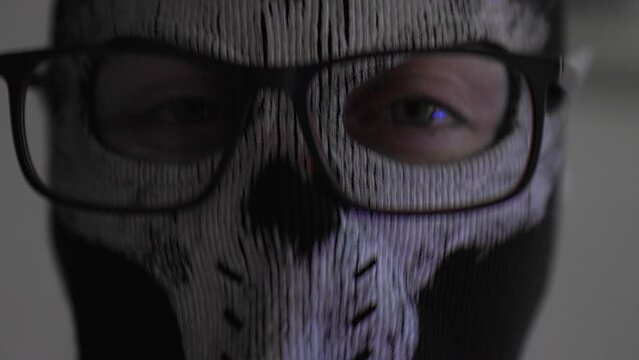 Portrait of a woman in close-up wearing a balaclava with glasses on her face. The police flashing light is shining. The concept of crime.