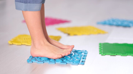 Little boy steps on orthopedic massage mats with different stiffness and texture. Feet Massage Using Trigger Point Spiky Massage Ball. Myofascial Release. close up.