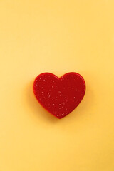 Small red heart on bright yellow background. Love concept. Flat lay.