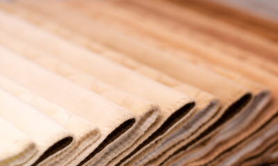 Fabric texture close up. Fabric swatches in different colors are stacked for selection. A variety of shades of upholstery material for furniture and interior. A set of multi-colored rolls of material.