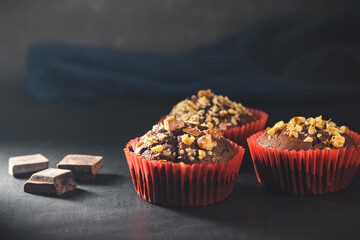 Homemade chocolate muffins or cupcakes sprinkled of nuts on dark background