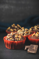 Homemade chocolate muffins or cupcakes sprinkled of nuts on dark background