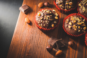 Homemade chocolate muffins or cupcakes sprinkled of nuts on a wooden board