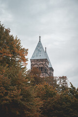 The steeples of Lund cathedral peeking up behind autumn colored trees