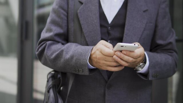 Man in elegant suit typing on smartphone, chatting with women in social networks, communicating with friends or relatives in online messengers, replying emails, close-up
