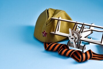 23 February, 9 May background - George ribbon, military cap and wooden plane on blue background....