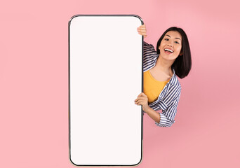 Cheerful asian lady showing big white empty smartphone screen