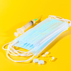 Masks and  syringe on yellow background. Close up. Isolated