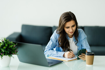 Portrait of business woman use phone and make notice in notebook at office