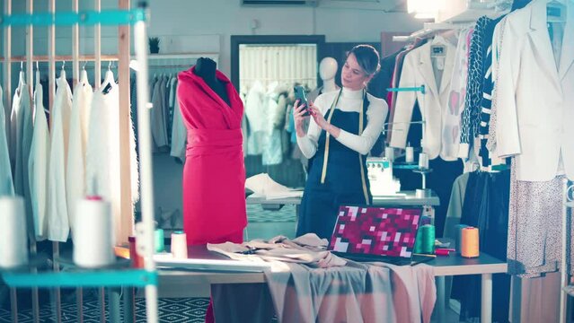 A seamstress is taking a picture of a dummy with a dress on it