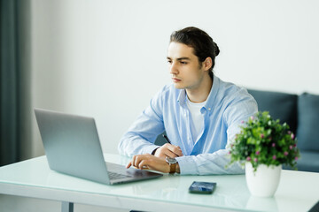 Young businessman working at home with laptop and papers on desk