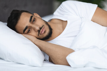 Fototapeta na wymiar Sleep Disorders. Upset Arab Man Lying In Bed With Open Eyes. Closeup