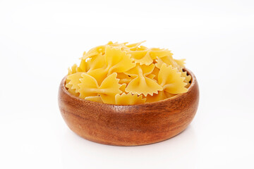 Uncooked pasta in wooden bowl on white background.