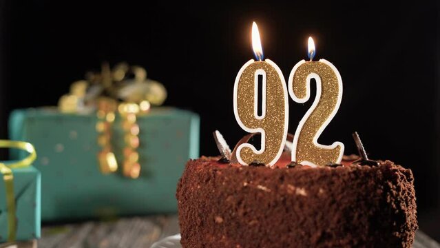 Birthday candle number ninety two on a sweet cake on the table, 92nd birthday. Fire from the lighter, blow out the holiday candle.