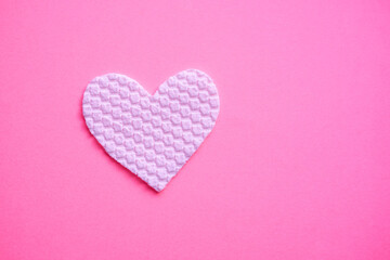 White fabric heart on pink table. Copy space on the right. Art love card.