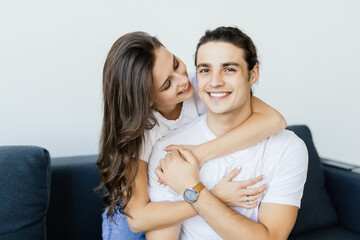 Portrait of young loving couple resting on a couch together at home and hugging