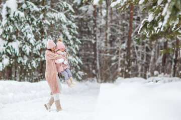 mom and daughter play in the winter forest
