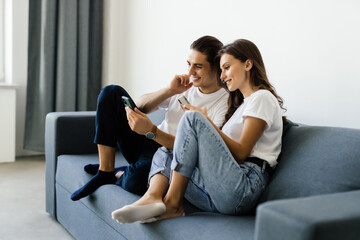 Obraz premium Man and woman sitting on a couch and holding smartphones in their hands.