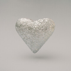 Crumpled arge silver heart made of aluminum foil. Minimal concept of Valentine's Day with a gray background