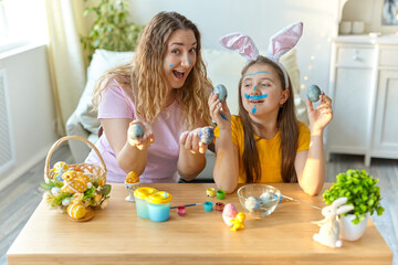 Mother and her daughter playing with painted eggs.