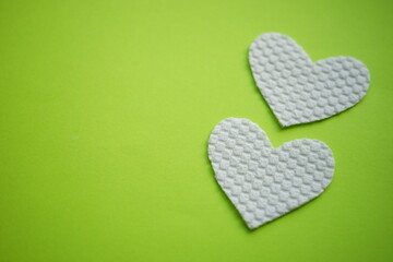 Two white fabric hearts on lime green table, copy space