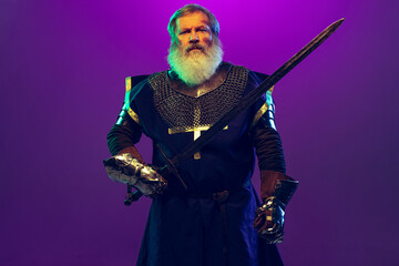 Portrait of senior greybearded man, brave and brutal medieval warrior or knight in armor with sword...