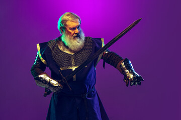 Portrait of senior greybearded man, brave and brutal medieval warrior or knight in armor with sword...