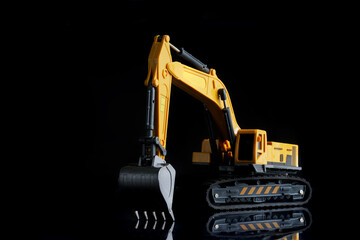 Large yellow toy crawler excavator on a black background with reflection. The concept of...