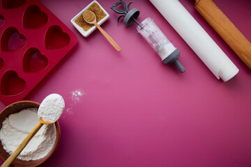 Fototapeta na wymiar Preparing for baking: heart-shaped silicone mold, rolling pin, confectionery syringe, glaze, flour, sugar. Valentine's day concept
