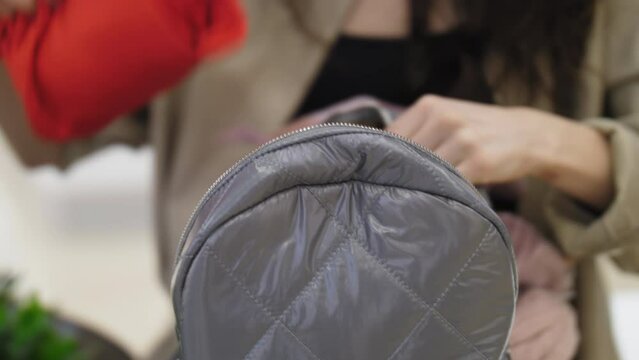 The girl pulls things out of the backpack. Close-up of hands and a backpack against the background of a young girl with long hair.