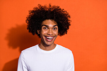 Photo of young cheerful man good mood comic humor laugh chevelure isolated over orange color...