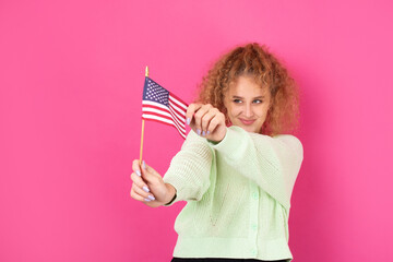 A young happy girl with a smile on her face holds an American flag in her hands. Symbol of patriotism and freedom.