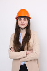 A girl architect in a suit and an orange construction helmet stands on a white background.