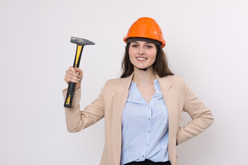 Girl engineer in an orange construction helmet with a hammer on a white background.