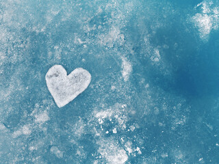 Obraz premium Heart made of snow or ice on a beautiful blue background. Ice texture, winter background with a place for an inscription. Winter, christmas, new year concept