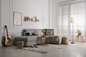 Living room with comfortable grey sofa and stylish interior elements near window