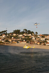 A firefighting helicopter collects water from the sea to put out a forest fire
