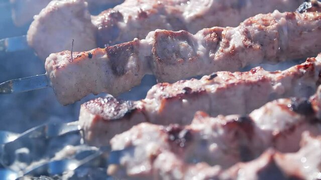 Bbq meat skewers grilling on charcoal grill. Grilled juicy pork shish kebab cooking on skewers on charcoal grill.