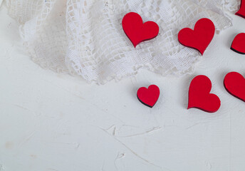 Red hearts on openwork white fabric on a white background. Copy space. Valentine's day concept.