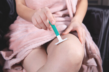 Obraz na płótnie Canvas young woman shaves her legs